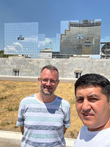 Two men standing in front of a modern building with a glass facade. 2