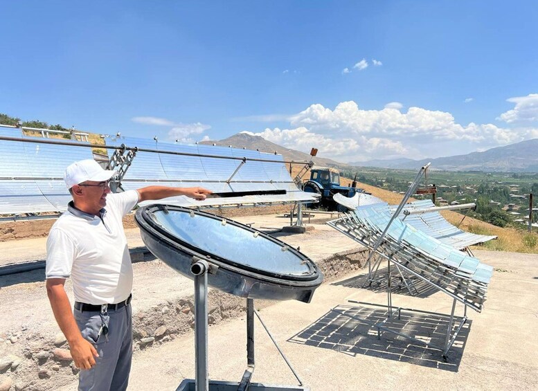 A person inspecting solar panels on a sunny day with mountains in the background. 4
