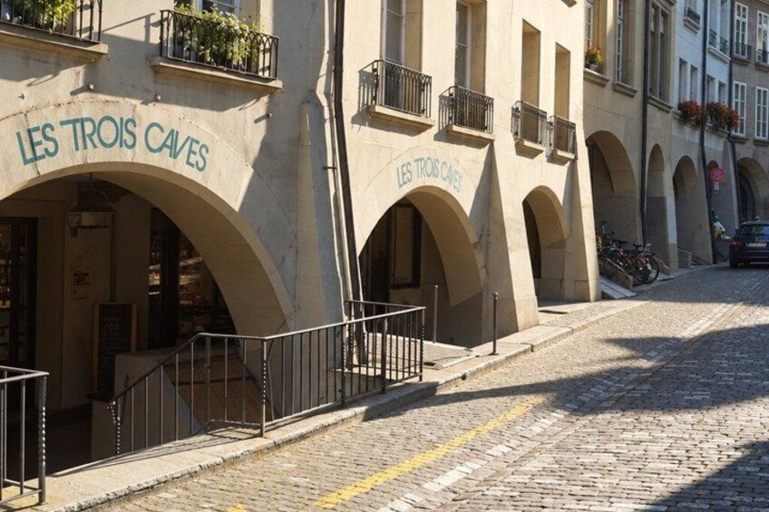 A cobblestone street with arches and a café named 'LES TROIS CAVES'. 2