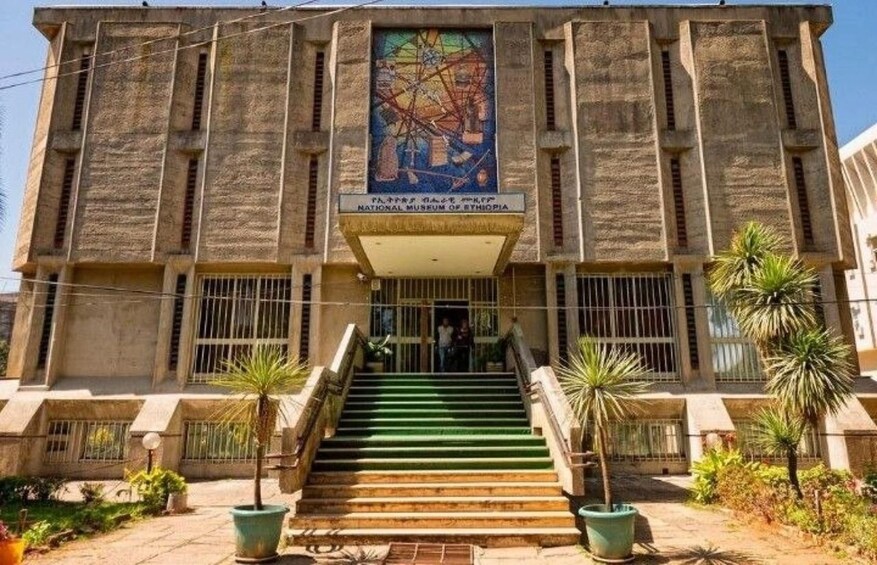 The National Museum of Ethiopia with a mural, steps, and palm trees. 1