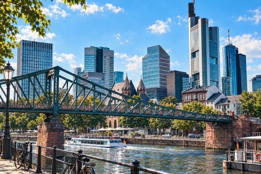 A cityscape with a prominent green bridge over a river, modern skyscrapers, and a historic building. 3