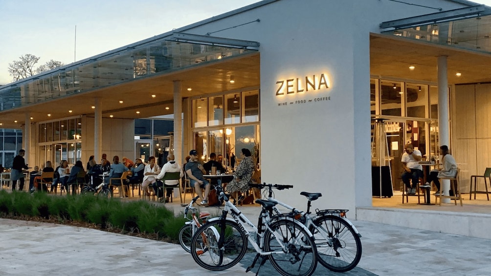 An outdoor seating area with bicycles parked in front of a building with a sign reading 'ZELNA'. 4
