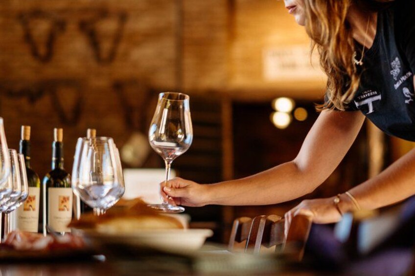 A person holding a wine glass at a bar with bottles and glasses on the counter. 4