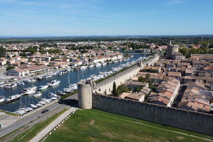 A coastal city with a historic fortification, a marina with boats, and a clear sky. 3