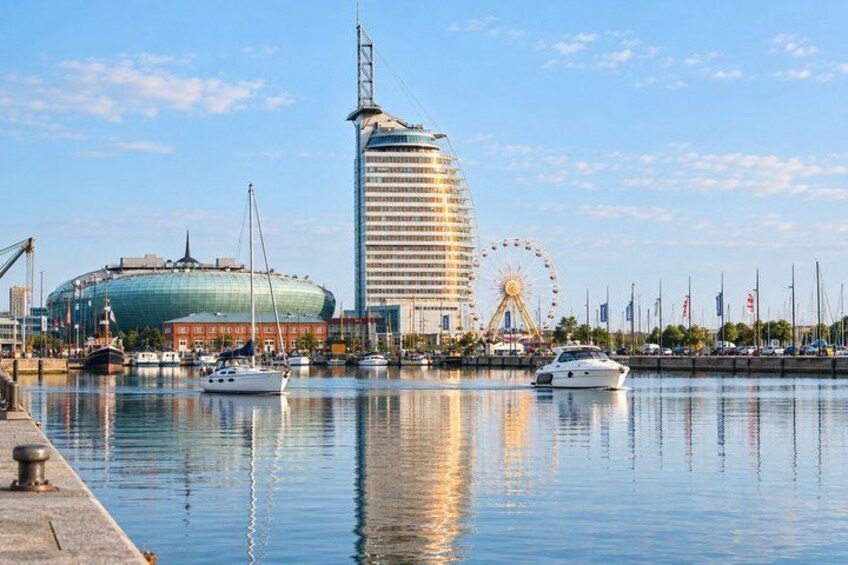 A waterfront with a sailboat, a Ferris wheel, and a distinctive modern building. 2