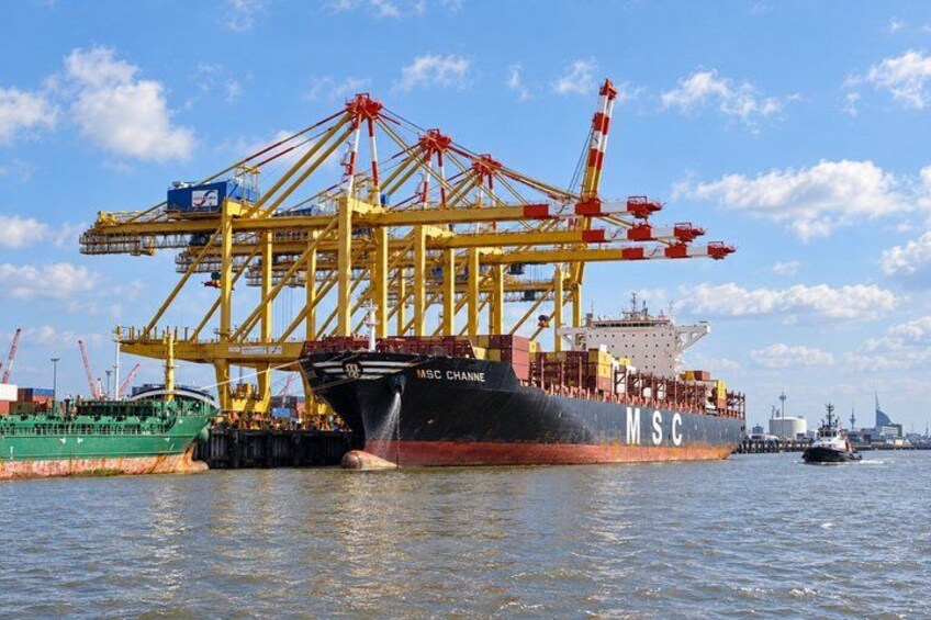 A large cargo ship docked at a port with cranes loading containers. 3