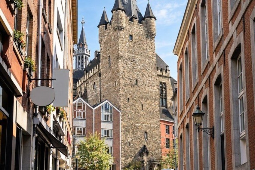 A historic stone tower with a clock, surrounded by traditional European buildings. 5
