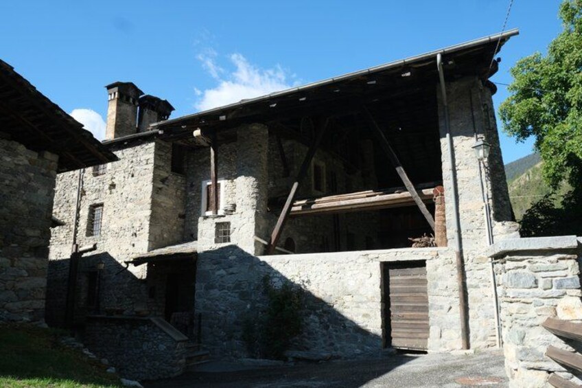 A stone building with wooden beams, a wooden door, and a stone staircase. 1