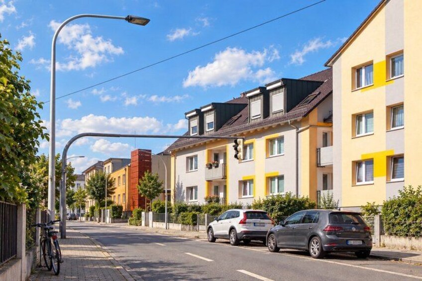 A residential street with multi-story buildings, parked cars, and a bicycle. 5