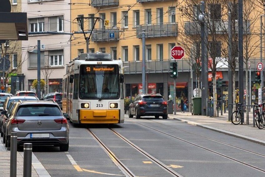 A tram with the number 53 approaching a stop sign on a city street. 4