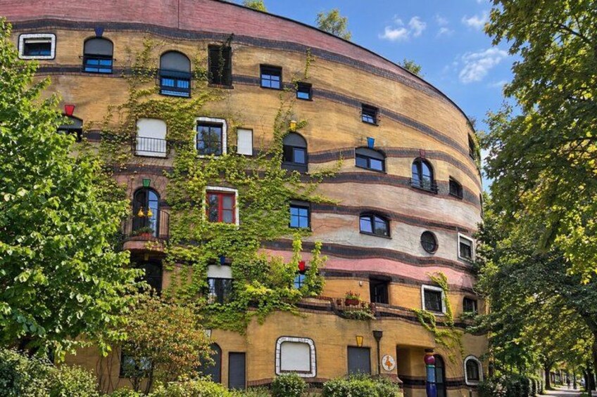 A curved building with multiple windows and balconies, surrounded by trees. 3