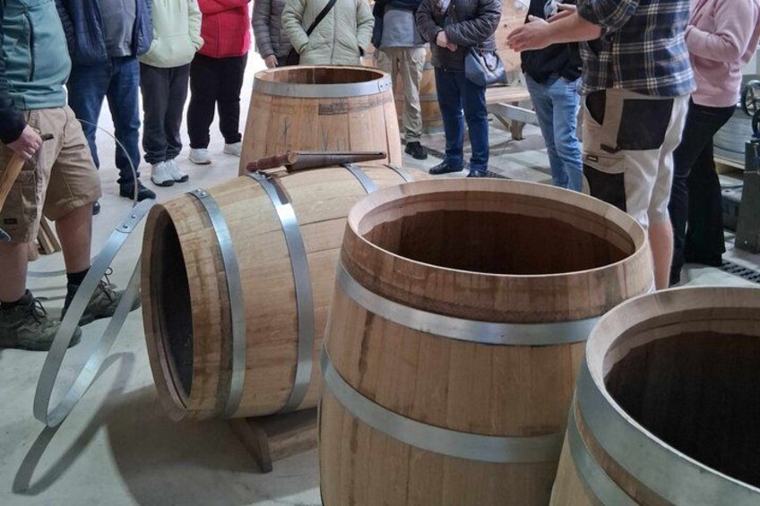 Wooden barrels with metal bands, likely used for aging wine or spirits, in a warehouse or storage setting. 1