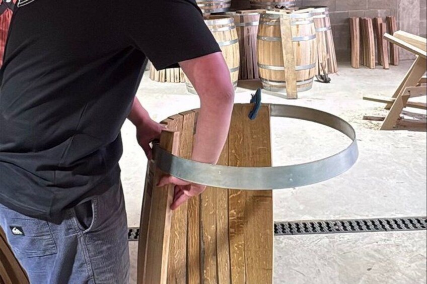 A person working with a wooden barrel and a metal ring. 3
