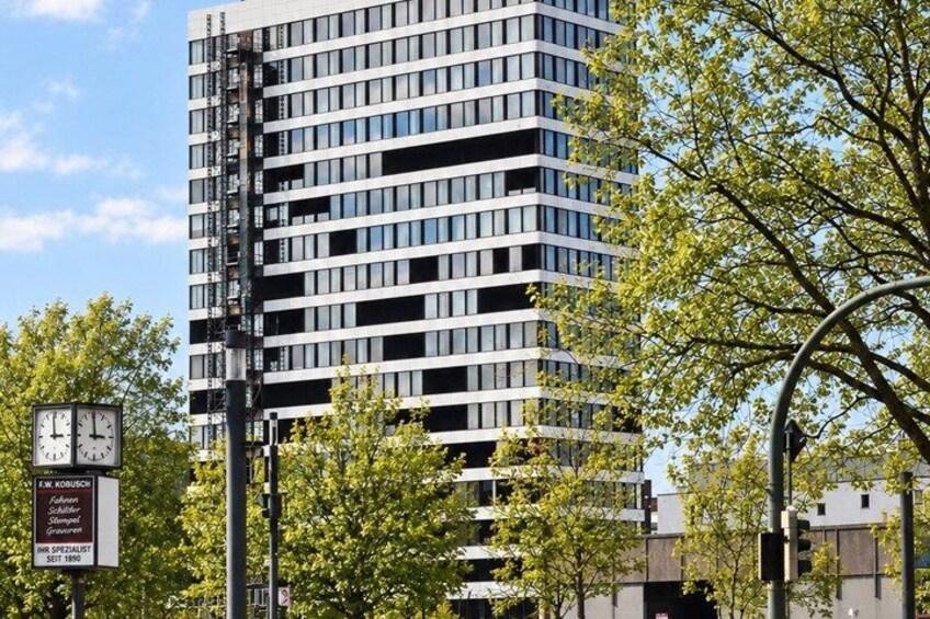 A modern high-rise building with a clock and a signboard in the foreground. 4