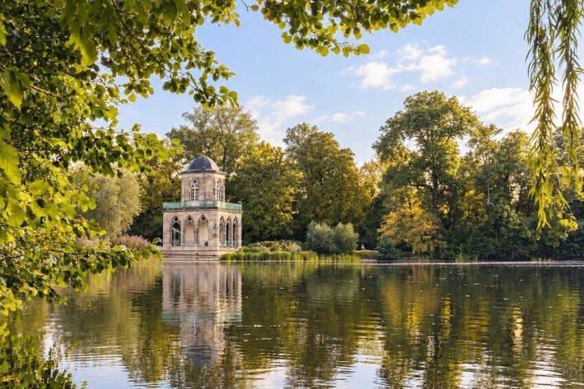 A gazebo-like structure by a calm lake surrounded by lush greenery. 2