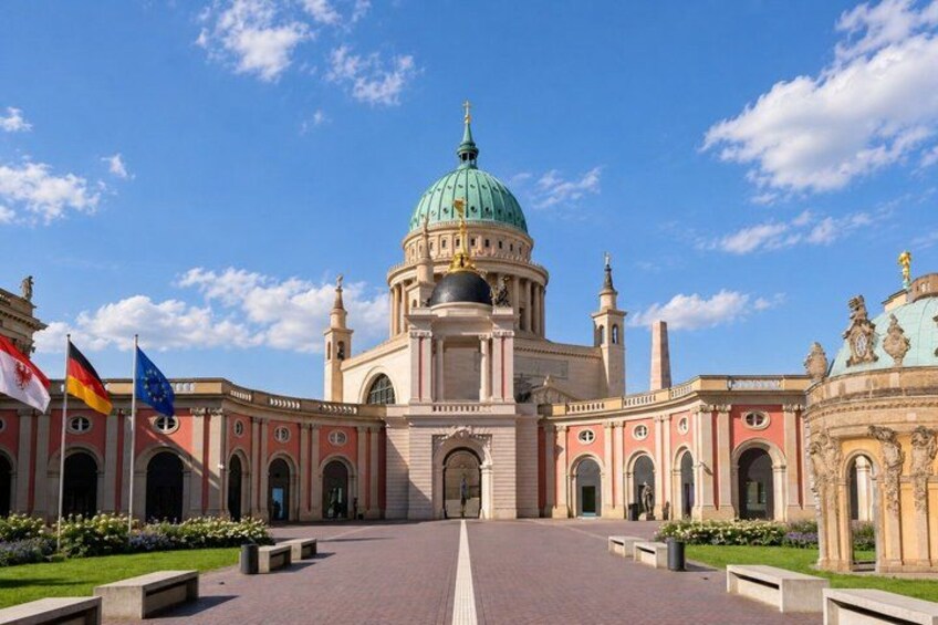 A grand building with a large dome, flags, and a clear sky. 3