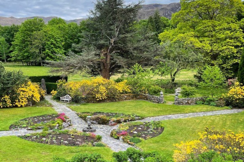 A lush garden with a winding path, various flowering plants, and a small white gazebo. 3