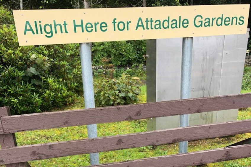 A wooden fence with a sign that reads 'Alight Here for Attadale Gardens.' 2