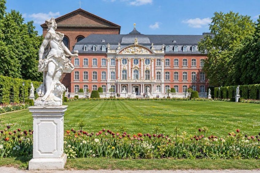 A grand building with a manicured lawn and a statue in the foreground. 5