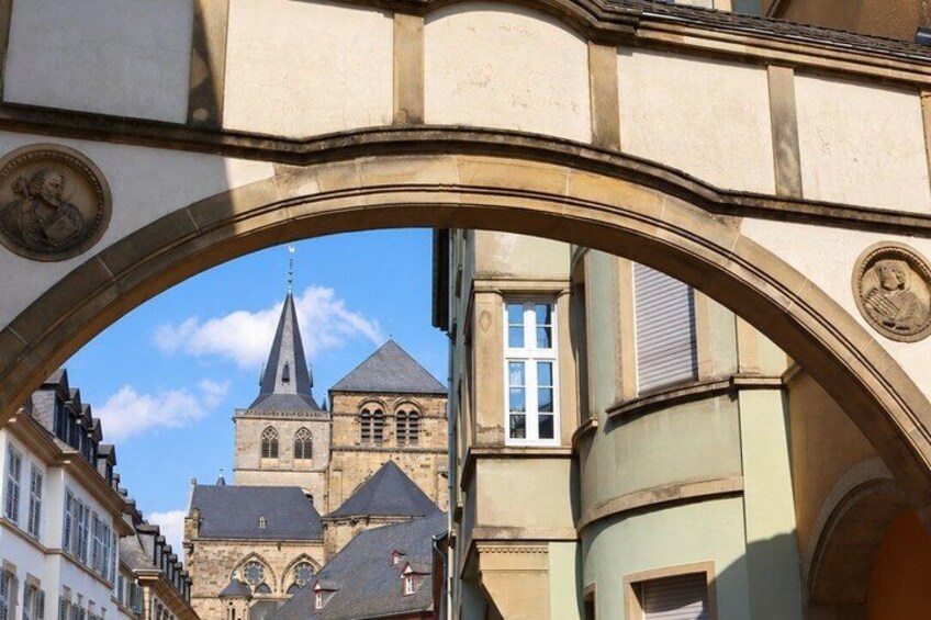 An archway framing a church with a spire and a clock tower. 4