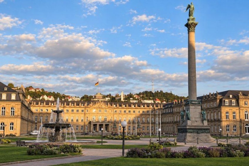 A historic building with a tall monument, a fountain, and a well-maintained garden. 2