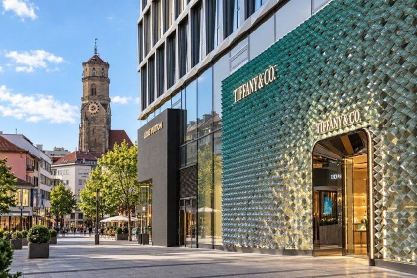A modern building with a Tiffany & Co. store, a clock tower, and a plaza with trees and benches. 4