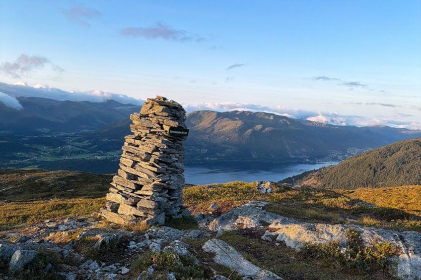 A stone cairn on a mountain ridge with a valley and lake in the background. 1