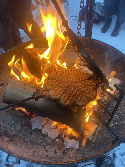 Un gofre cocinándose a la parrilla sobre fuego directo en una sartén de metal. 3