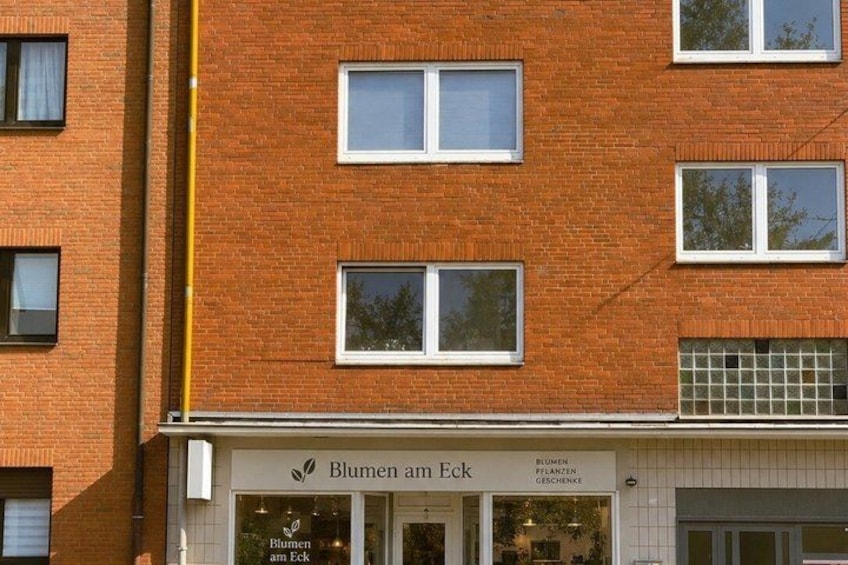 A brick building with multiple windows and a storefront named 'Blumen am Eck.' 2