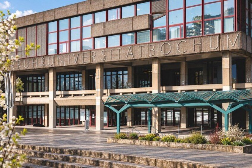 A building with the inscription 'RUPHUNIVERSITATBOCHUM' and a covered entrance area. 4