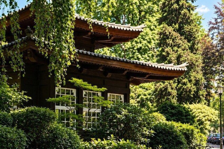 Un edificio japonés tradicional con tejado de tejas, rodeado de exuberante vegetación y árboles. 4
