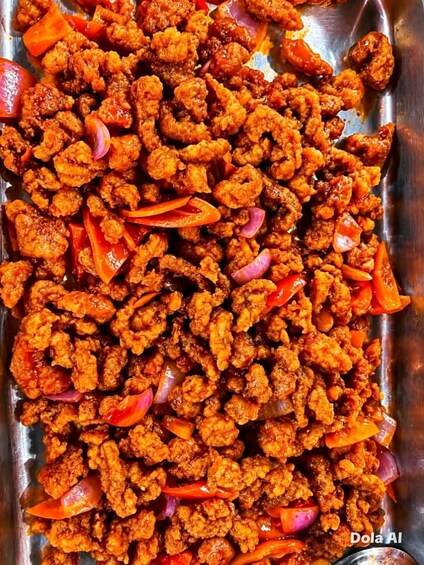 A tray of fried chicken pieces with red bell peppers and onions. 3