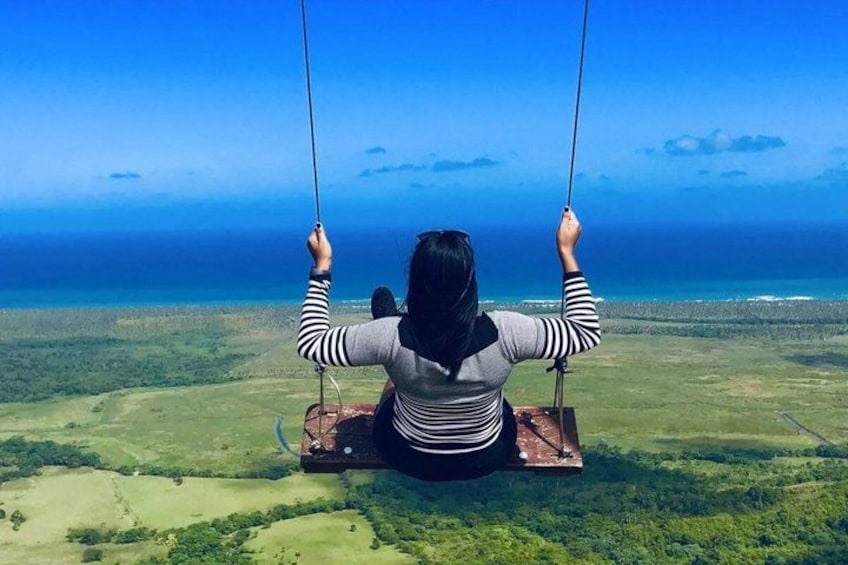 A person on a swing overlooking a coastal landscape. 1