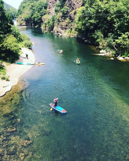 A river with kayaks and a paddleboarder. 1