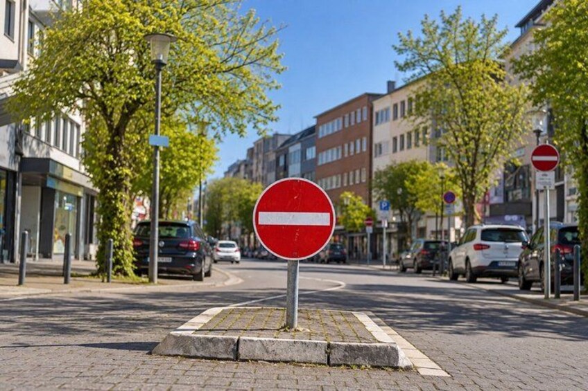 A city street with a no entry sign, parked cars, and buildings. 4