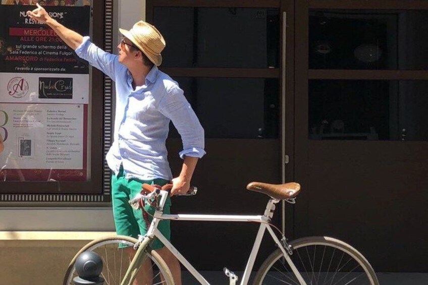 A person pointing at a signboard, standing next to a bicycle. 1