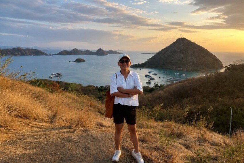 A person standing on a grassy hill overlooking a coastal landscape with a mountain and the sea. 3