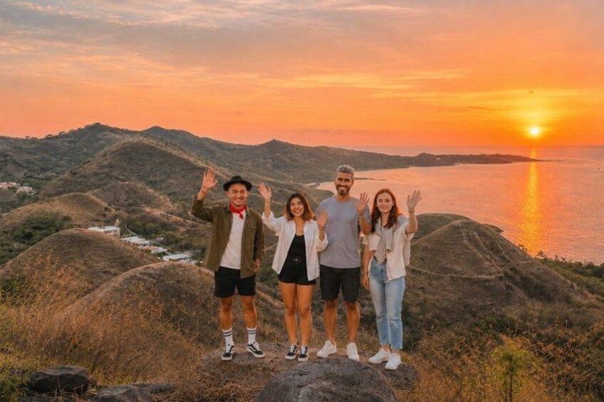 A group of people standing on a hill with a sunset in the background. 2