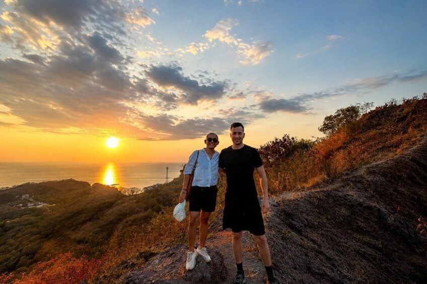 Two people standing on a hill with a sunset in the background. 4