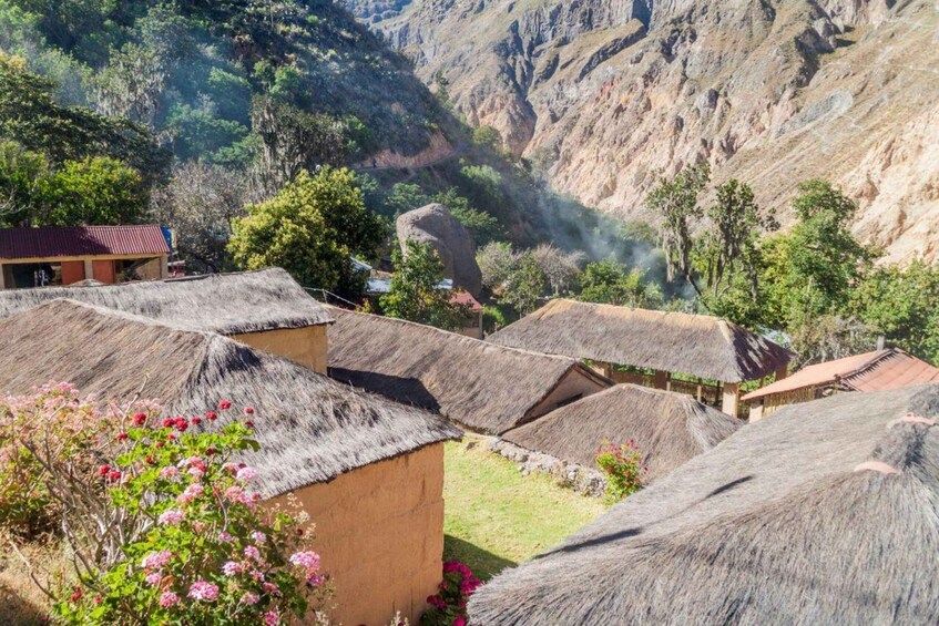 A village with thatched-roof houses nestled in a valley with steep cliffs. 5