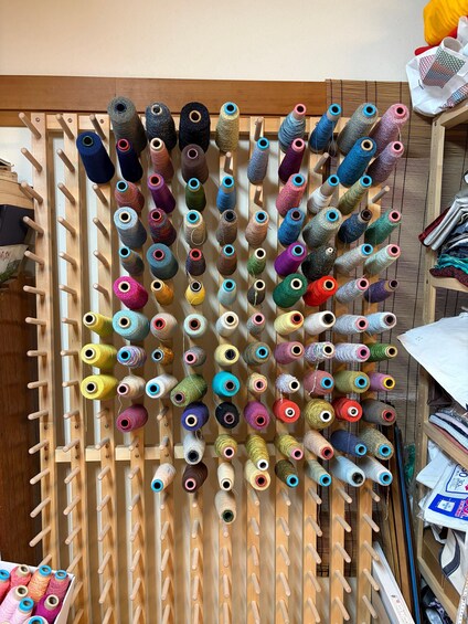 Een houten spoelhouder met verschillende gekleurde draadspoelen. 3