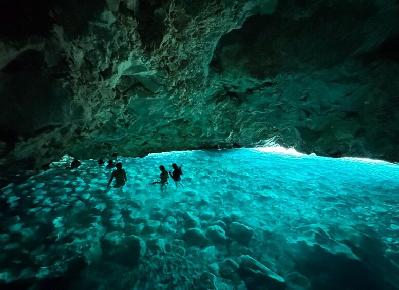 Una cueva con agua turquesa cristalina y gente nadando. 1