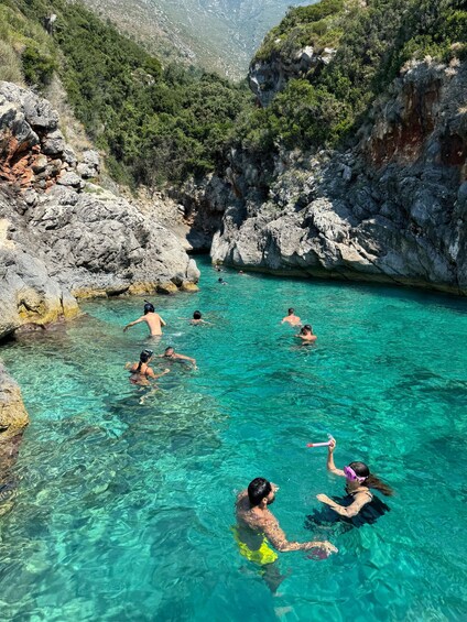 Personas nadando en una piscina turquesa cristalina rodeada de acantilados rocosos y vegetación. 2