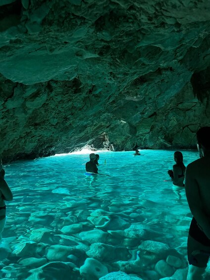Una cueva con agua turquesa cristalina y gente nadando. 5