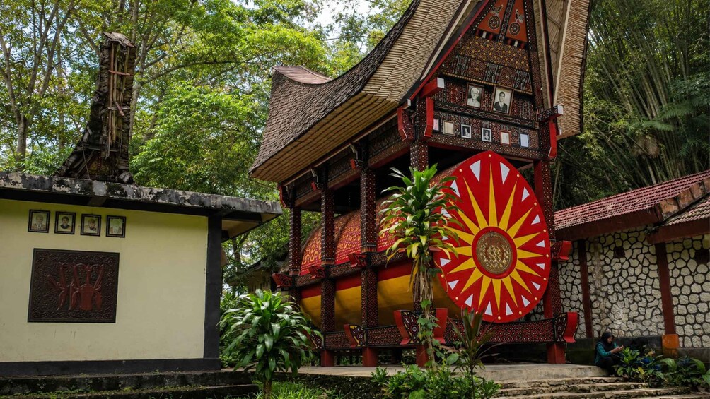 A traditional building with a large decorative sun wheel, surrounded by lush greenery. 1