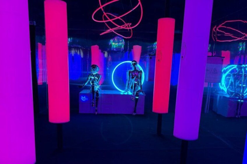 A futuristic exhibit with neon-lit structures and skeleton figures. 4