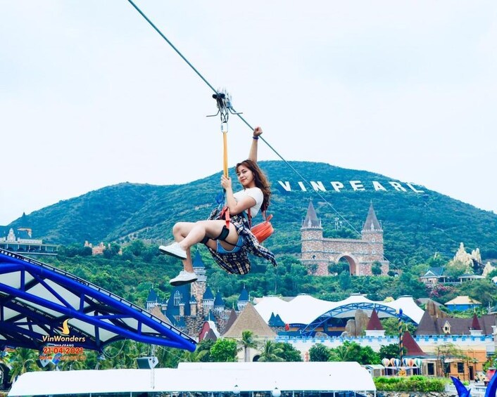 A person on a zip line with a mountain and amusement park in the background. 5