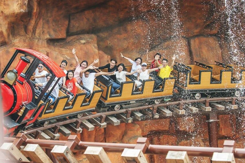 A wooden roller coaster with passengers, tracks, and a rocky background. 4