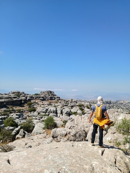 A hiker on rocky terrain with a clear sky. 1