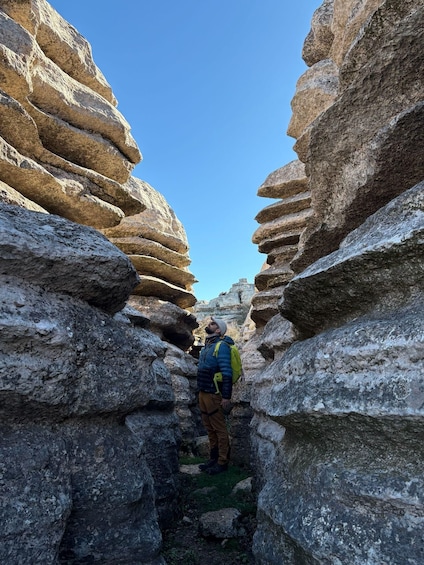 A person hiking through a narrow canyon with layered rock formations. 4